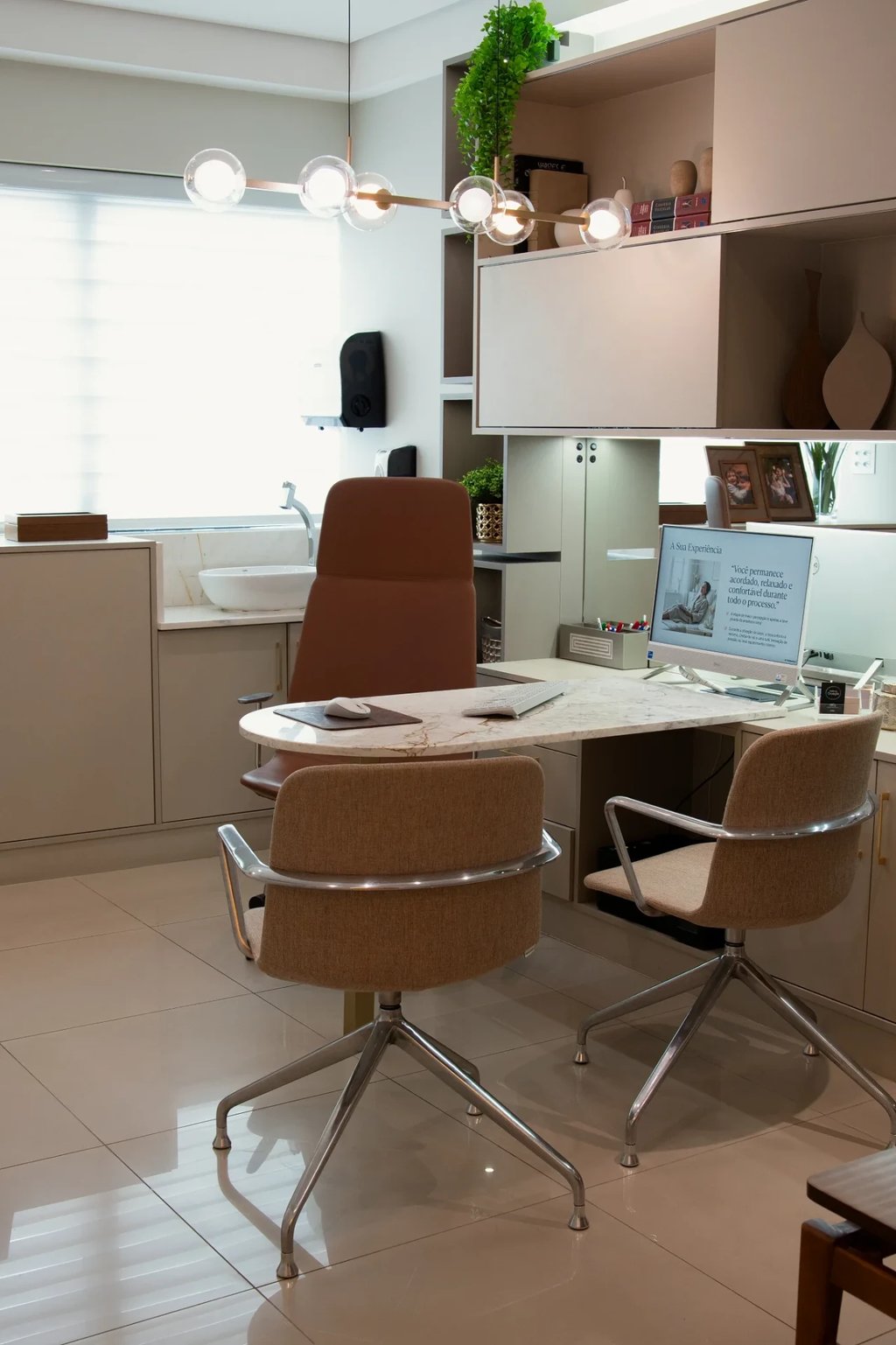 Consultório da Clínica La Vena com mesa de mármore, poltronas e estante de madeira